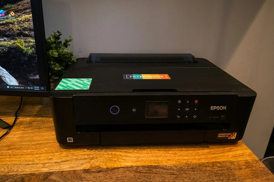 Black epson color printer next to monitor on wooden desk