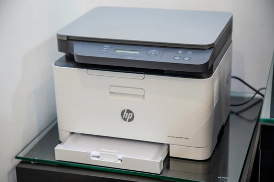 HP color printer on glass table in corner of room